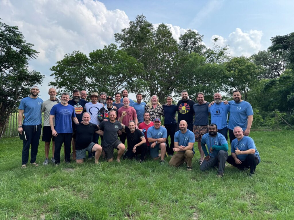 A group of veterans and program staff gathered in a field for a group photo.